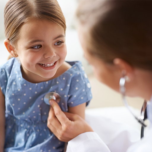 A smiling girl being examined with a stethoscope by a clinician