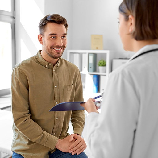 A man in an olive shirt talking with a clinician who is holding a clipboard