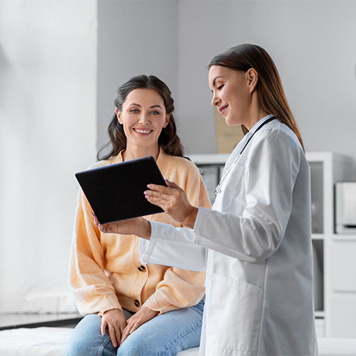 A woman seated with a doctor in a white coat who is showing her results on a tablet