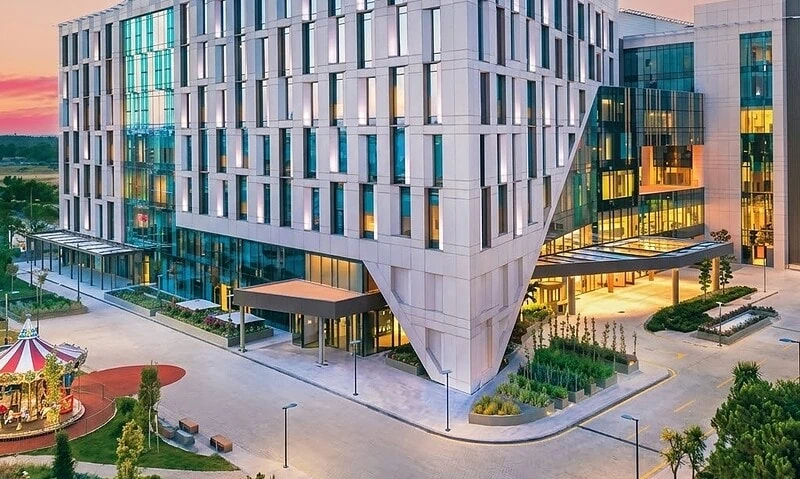 Modern Acibadem Kent Hospital building in Izmir at sunset.