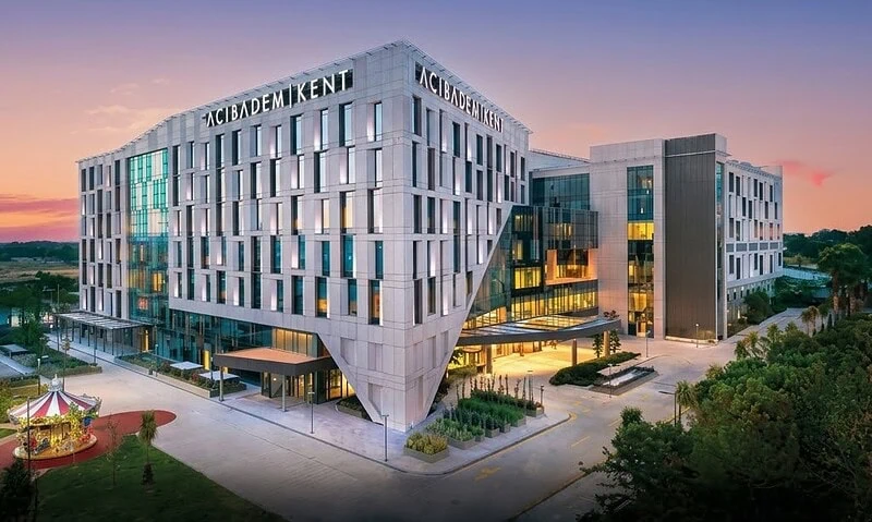 Modern Acibadem Kent Hospital building in Izmir at sunset.