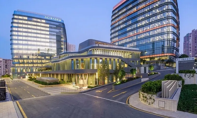 Modern Acibadem Atasehir Hospital building with glass facade at dusk.