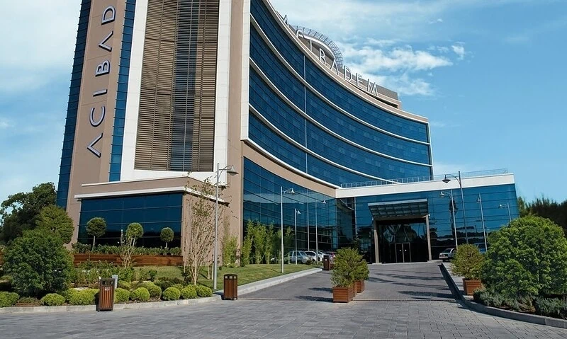 Modern hospital building with glass facade and landscaped entrance.