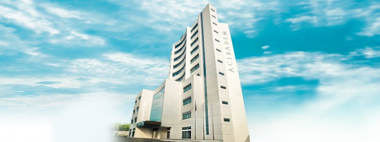 Acibadem Fulya Hospital modern high-rise building with blue sky background.
