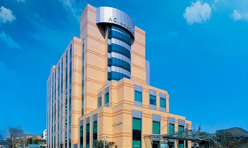 Modern Acibadem Kozyatagi Hospital building with blue sky background.