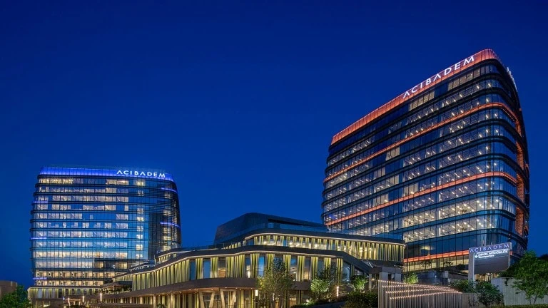 Acibadem Hospitals Group modern hospital buildings illuminated at night, showcasing advanced healthc.