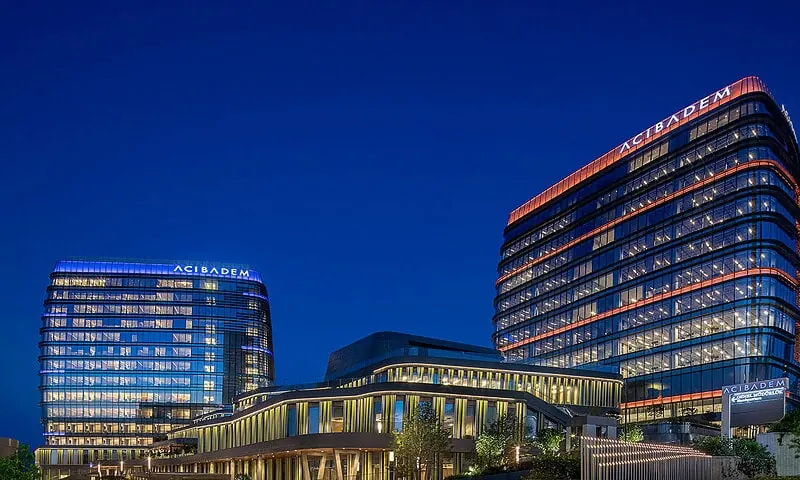 Acibadem Hospitals Group modern hospital buildings illuminated at night, showcasing advanced healthc.