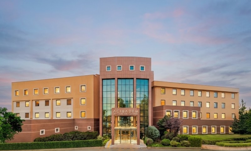 Modern hospital building with glass entrance and landscaped surroundings.