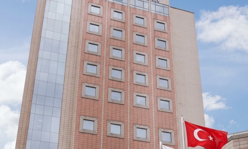 Modern hospital building with flags in front, part of Acibadem Hospitals Group.