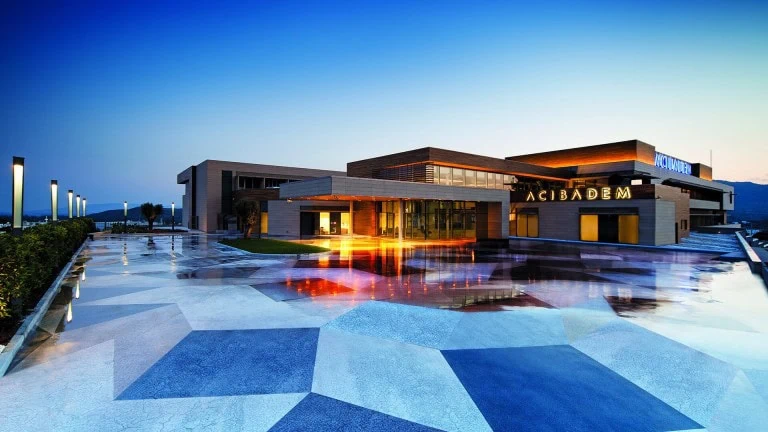 Exterior view of Acibadem Bodrum Hospital at dusk with modern architecture.