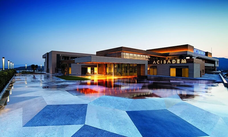 Exterior view of Acibadem Bodrum Hospital at dusk with modern architecture.