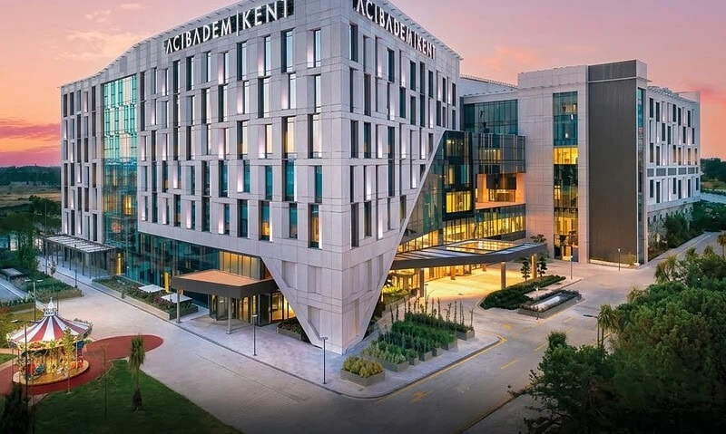 Modern Acibadem Kent Hospital building in Izmir at sunset.