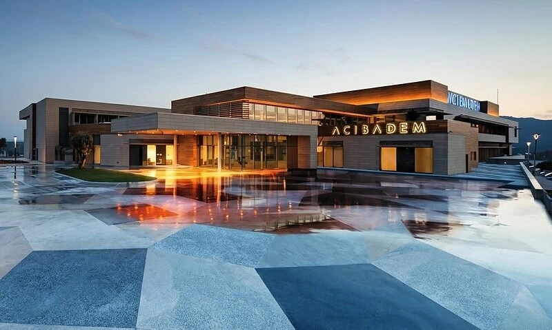 Modern exterior of Acibadem Bodrum Hospital at dusk with illuminated entrance.