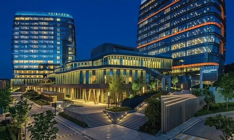 Modern Acibadem Atasehir Hospital buildings at night with illuminated windows.