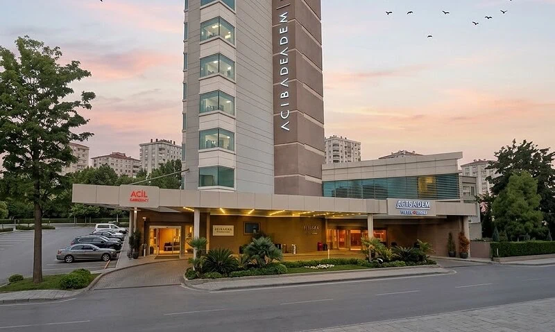 Modern hospital building with Acibadem sign at sunset.