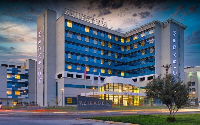 Modern Acibadem hospital building with blue and white exterior at dusk.