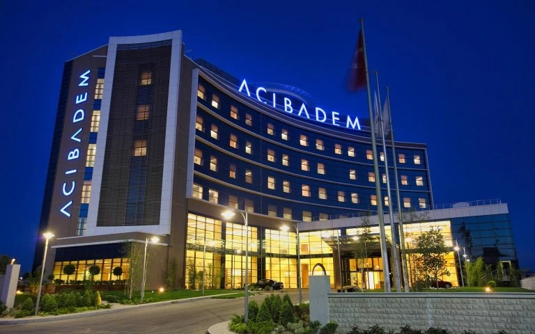Acibadem Hospitals Group modern hospital exterior at night with illuminated signage.